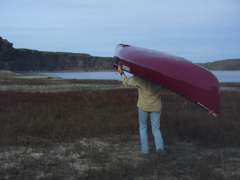 Cris Currie portages a canoe across a dry area between the two ends of Coffeepot Lake, where water levels are very low in March 2015. (Nora Searing)