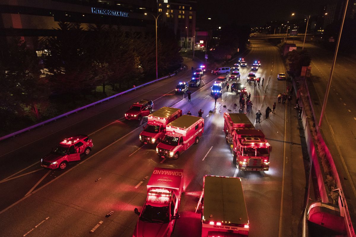 Emergency personnel work at the site where a driver sped through a protest-related closure on the Interstate 5 freeway in Seattle, authorities said early Saturday, July 4, 2020. Dawit Kelete, 27, has been arrested and booked on two counts of vehicular assault.  (James Anderson)