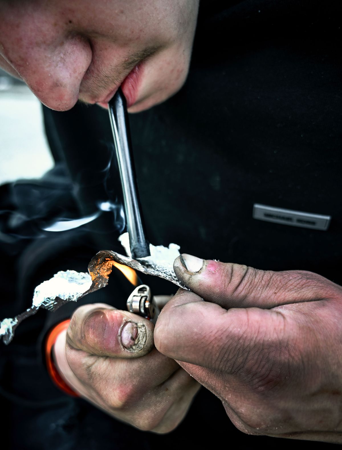 A man takes a hit of fentanyl after heating a ground-up pill on foil on March 20 in the area of 2nd Avenue and Division Street.  (COLIN MULVANY/THE SPOKESMAN-REVIEW)