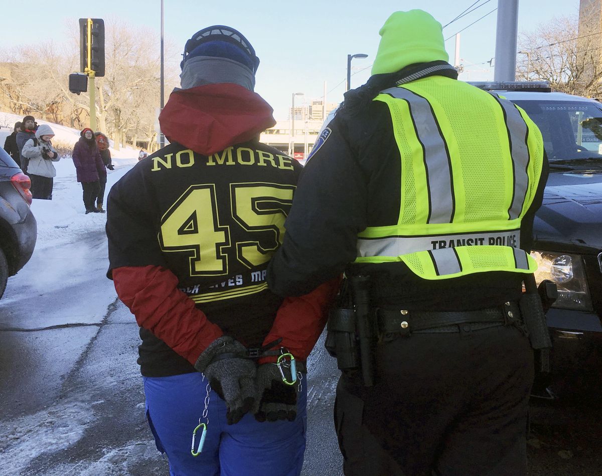 A transit police officer escorts a protester away after protesters formed a human blockade Sunday, Feb. 4, 2018, across light-rail tracks near U.S. Bank Stadium in Minneapolis where the Super Bowl between the New England Patriots and the Philadelphia Eagles was scheduled to kick off later in the evening. (Shari Gross / Star Tribune)