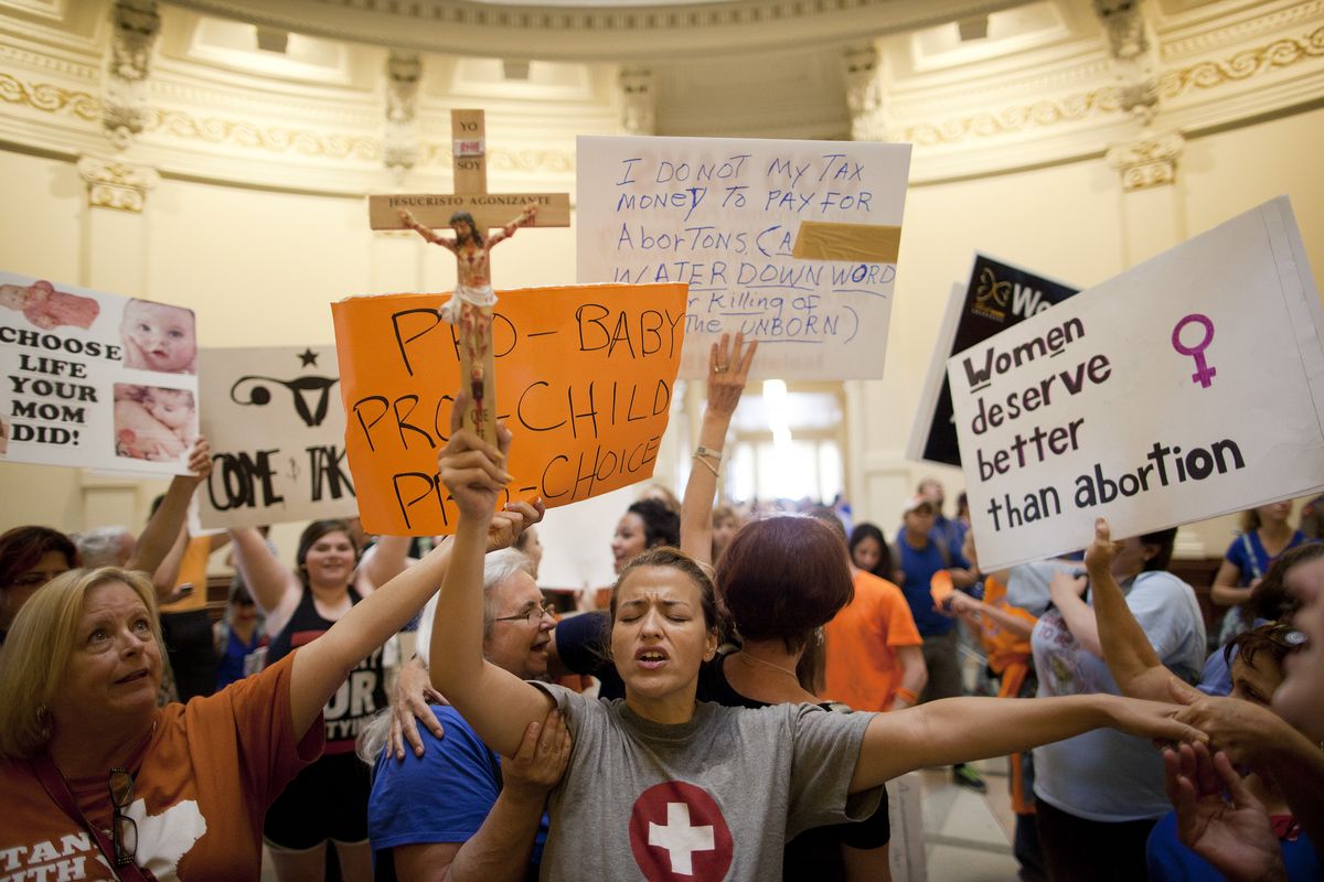 Abortion opponent Katherine Aguilar holds a crucifix and prays while opponents and supporters of abortion rights gather in the state Capitol rotunda in Austin, Texas, on Friday. (Associated Press)