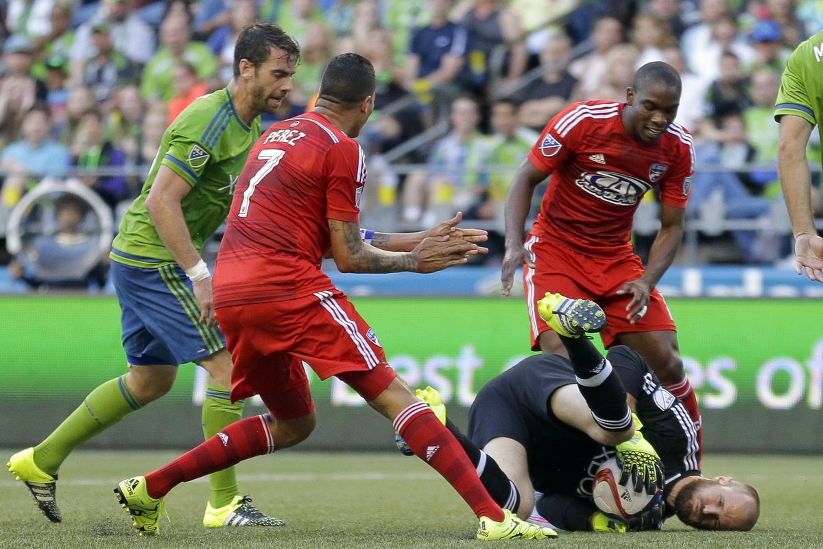Sounders goalkeeper Stefan Frei, lower right, dives on the ball as Dallas