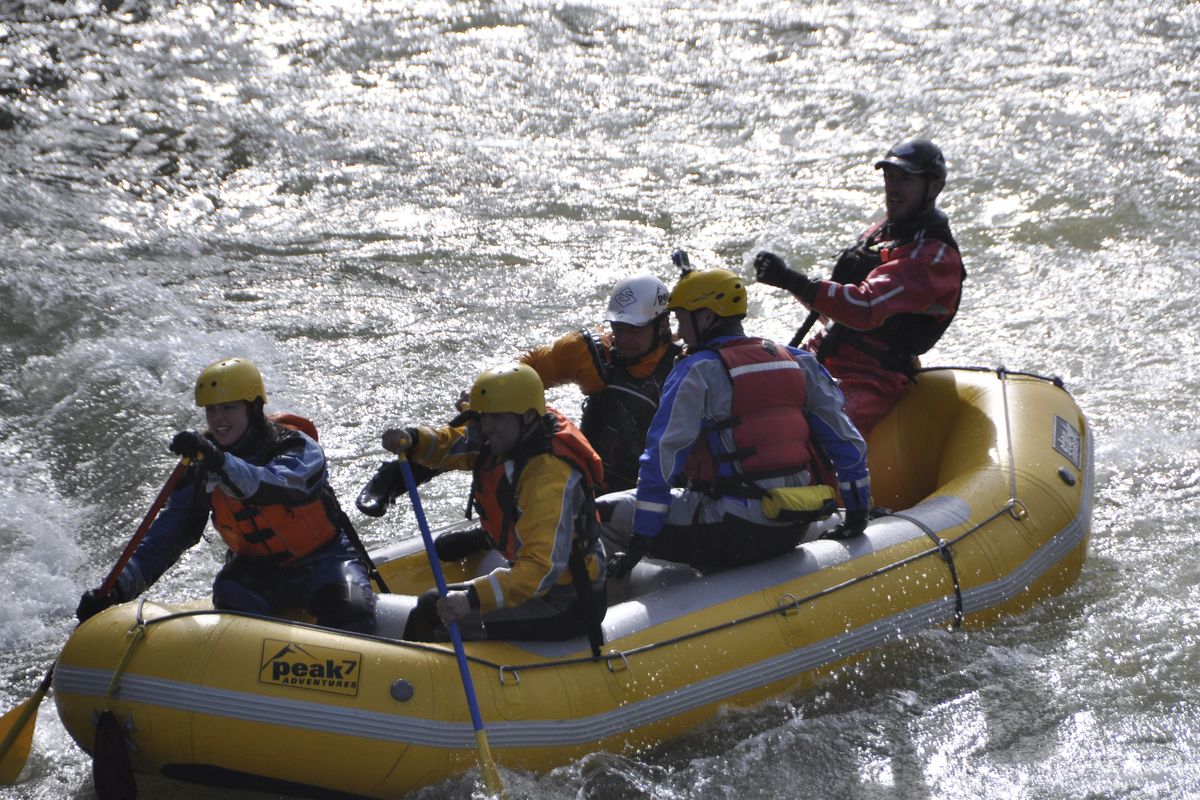 A raft of Peak 7 Adventures paddlers busts through the first big rapid entering the Bowl and Pitcher Area above the Riverside State Park suspension bridge with river flows around 16,000 cfs on March 13, 2016. In following photos, an ejected rafter is rescued. (Rich Landers)