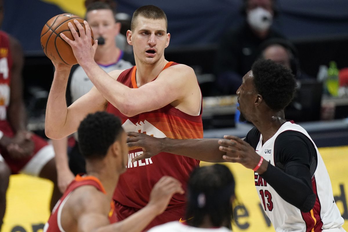 Denver Nuggets center Nikola Jokic, left, looks to pass the ball as Miami Heat center Bam Adebayo defends in the first half of an NBA basketball game Wednesday, April 14, 2021, in Denver. (Associated Press)