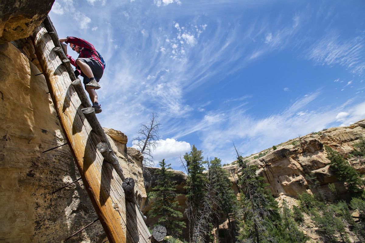 Seth Boster climbs into Lion Canyon on Aug. 10 to explore the Tree House cliff dwelling.  (Christian Murdock/Tribune News Service)