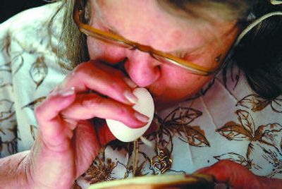 
Eileen Starr blows the contents of an egg into a bowl after poking a hole in the shell. 
 (The Spokesman-Review)