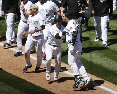 Colorado Rockies' Nolan Arenado, front right, is restrained by Carlos Gonzalez, center, as Gerrardo Parra, left, keeps an eye on the San Diego Padres dugout after Arenado rushed the mound following getting hit by a pitch from Padres starting pitcher Luis Perdomo in the third inning of a baseball game Wednesday, April 11, 2018, in Denver. (David Zalubowski / AP)