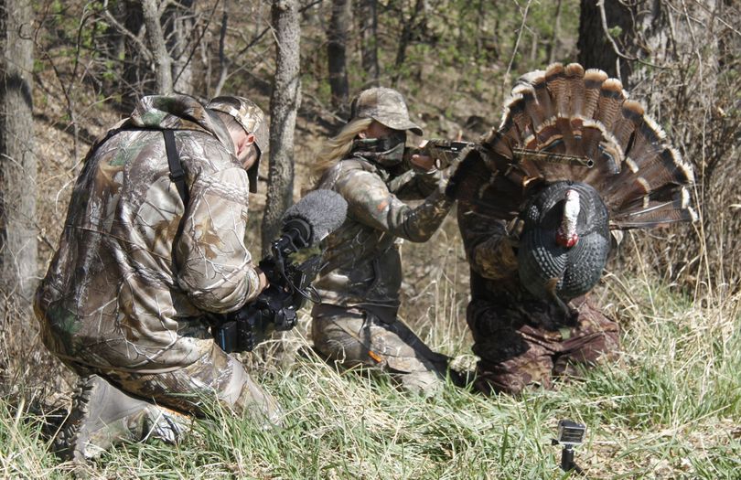In this April 11, 2014 photo, Theresa Vail, Miss Kansas, shoots through a gobbler decoy's feathers during filming of a television hunting series called 