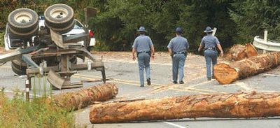 
Washington State Patrol troopers walk through the scene of a crash on Highway 101 near Humptulips, Wash., on Tuesday. Daniel Johnson, 46, and Anthony Qamar, 62, two Seattle scientists who were on the Olympic Peninsula doing research on earthquakes, died after their car was struck by logs that tumbled off a log truck traveling in the opposite direction. 
 (Associated Press / The Spokesman-Review)