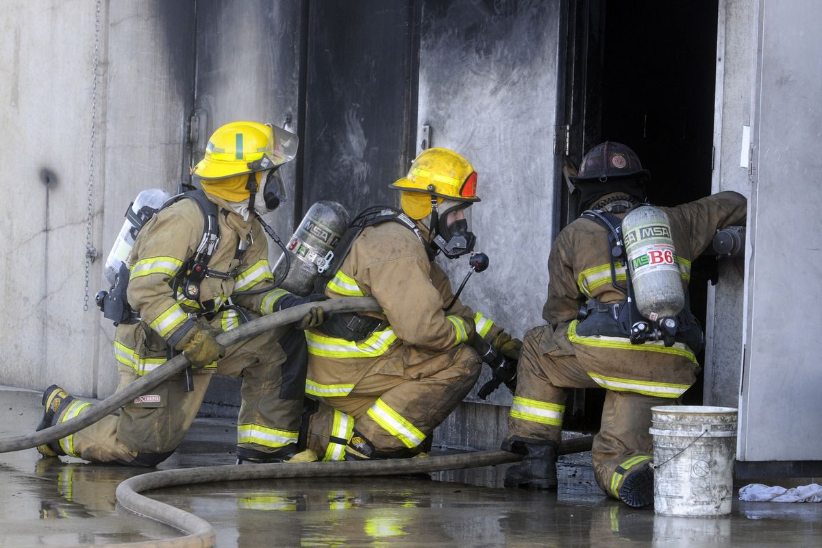 Firefighter recruits are taught to advance a hose line into a structure to extinguish a fire at the fire training tower at the Spokane Valley Fire Training Center during an 11-week training session for five Spokane Valley and 16 Spokane city recruits. (J. BART RAYNIAK)