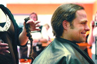 
Jesse Hansen is all smiles as The Man Shop manager and stylist Kim Fields holds up his ponytail moments after she cut it off. Hansen had his hair cut to honor his late brother-in-law and to raise funds for Candlelighters of the Inland Northwest. 
 (Jed Conklin / The Spokesman-Review)