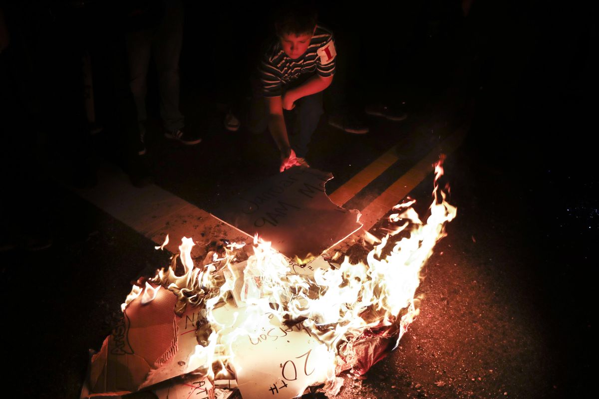 A young protestor feeds a fire of protest signs during a demonstration outside the National Press Building ahead of the presidential inauguration, Thursday, Jan. 19, 2017, in Washington. (John Minchillo / Associated Press)