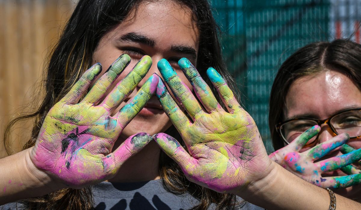 Shadle Park High School Leadership Class students Gage Bogue, left, and Miya Eckel display their painted hands Friday after helping Westview Elementary School third-graders create a mural on an alley wall in the Garland District.  (DAN PELLE/THE SPOKESMAN-REVIEW)