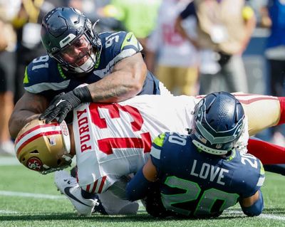 Seahawks defensive tackle Byron Murphy II, left, and safety Julian Love sack San Francisco 49ers quarterback Brock Purdy during a Sept. 7 game in Seattle.  (Jennifer Buchanan/Seattle Times)