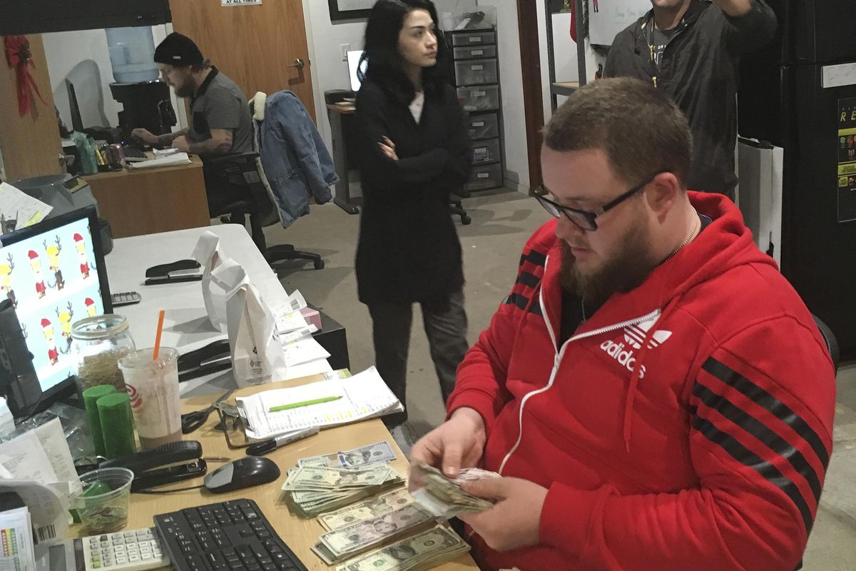 In this Wednesday, Dec. 27, 2017, photo Employee Joshua Wilson counts cash at the Golden State Greens marijuana dispensary in San Diego. A few dozen California shops have cleared a final hurdle to sell marijuana for recreational use starting Monday, Jan. 1, 2018, and regulators will work through the weekend to grant more licenses. (Elliot Spagat / Associated Press)