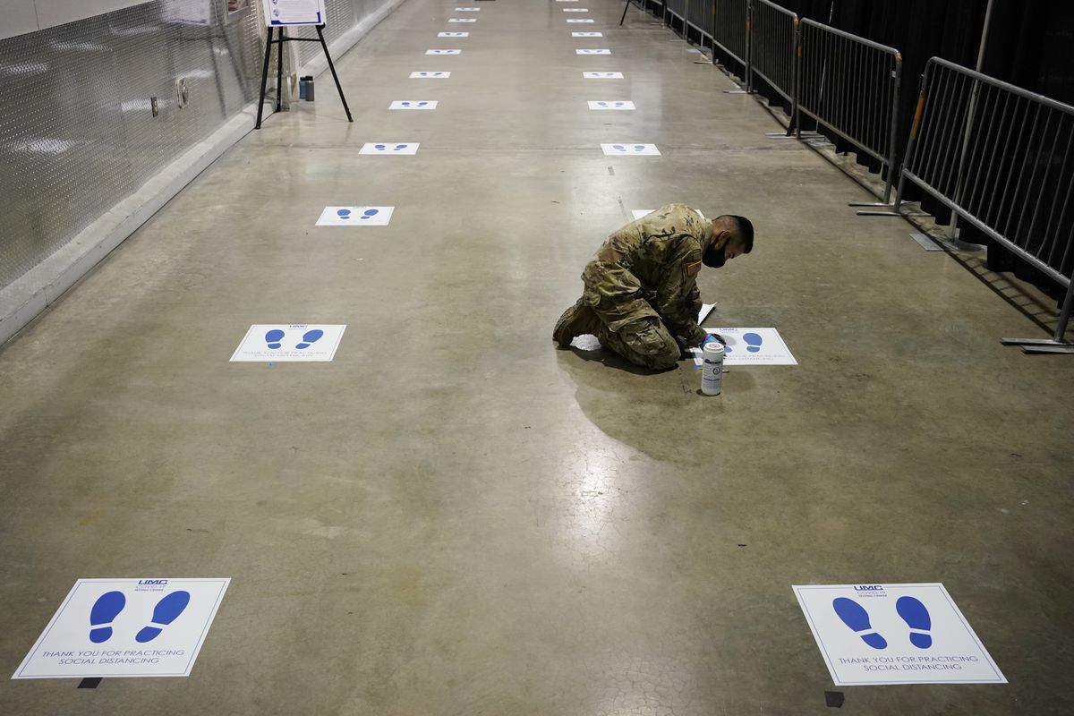A member of the Nevada National Guard installs social distancing stickers while setting up a new temporary coronavirus testing site Monday, Aug. 3, 2020, in Las Vegas. (John Locher)