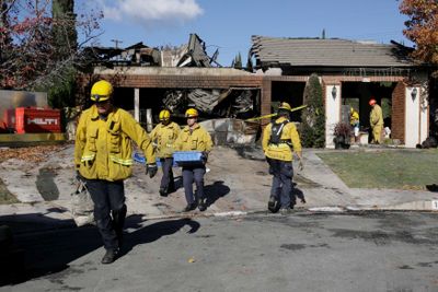 Los Angeles County firefighters remove items from the burned home Friday in Covina, Calif., that was set on fire during a Christmas Eve  shooting rampage.  (Associated Press / The Spokesman-Review)