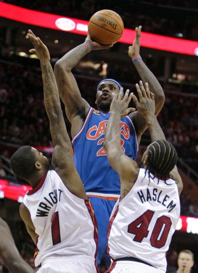 Cleveland‘s LeBron James shoots over Miami Heat forward Dorell Wright, left, and Udonis Haslem in the fourth quarter Thursday.  (Associated Press)