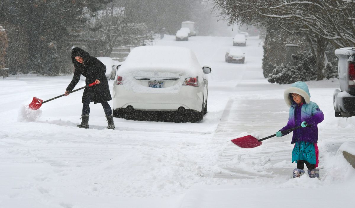 It was a team effort to clear the snow from the sidewalk and from around the car for Stacie Hempfhill and her daughter, Riley, on Monday near the corner of 33rd Avenue and Myrtle Street in Spokane after several inches fell during the morning hours. (Dan Pelle/THE SPOKESMAN-REVIEW)