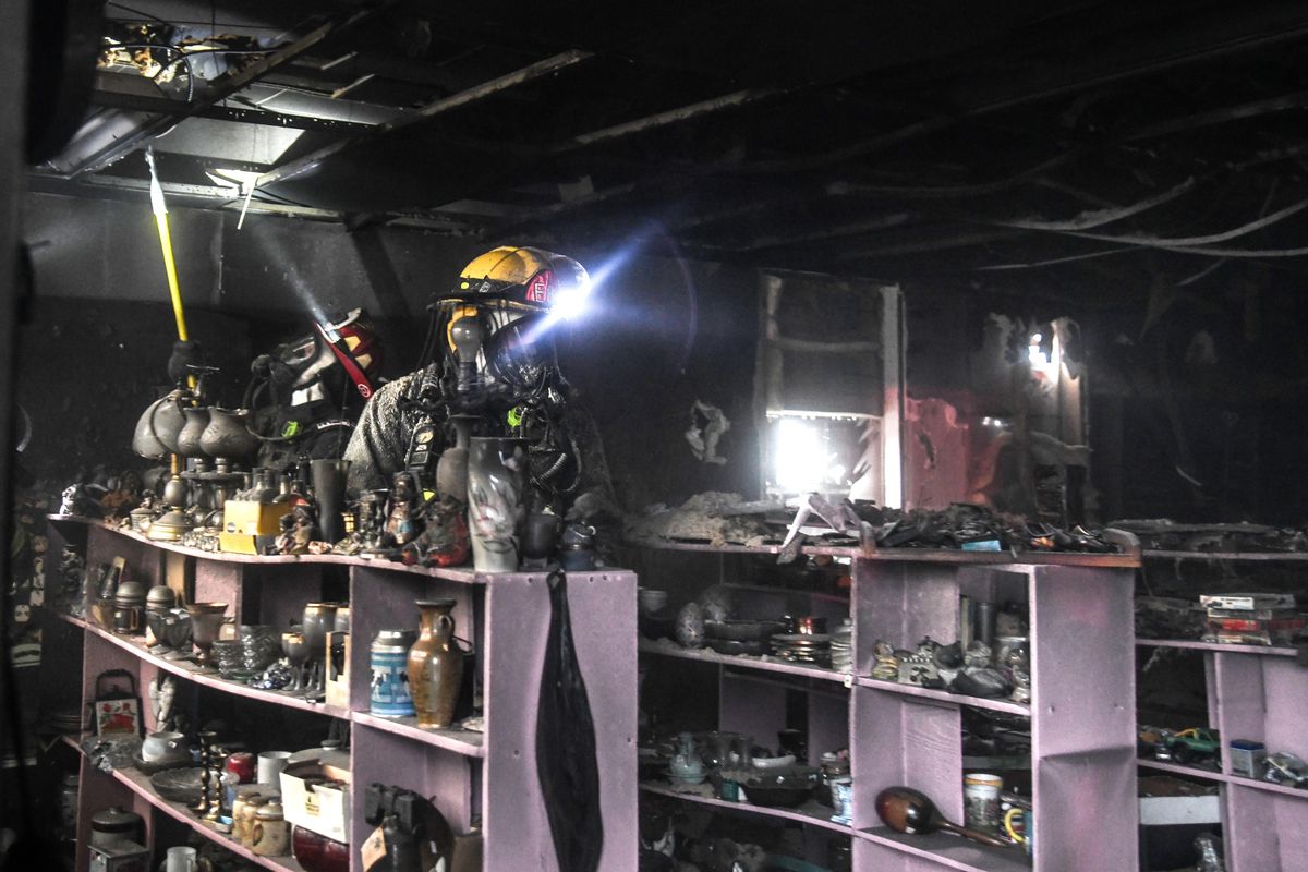 Spokane Valley firefighters look in the ceiling and surrounding area inside the Flea Market at 9400 E. Sprague after a fire Friday morning, April 5, 2019. (Dan Pelle / The Spokesman-Review)