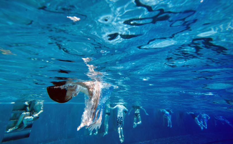 A boy jumps into the water on the occasion of the season opening of public swimming pools during warm and sunny weather in Munich, Southern Germany, Tuesday, May 1, 2012. (Joerg Koch / Dapd)