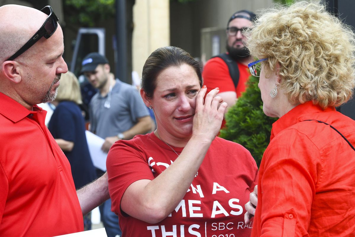 FILE - In this Tuesday, June 11, 2019 file photo, Jules Woodson, center, of Colorado Springs, Colo., is comforted by her boyfriend Ben Smith, left, and Christa Brown while demonstrating outside the Southern Baptist Convention