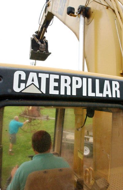 
Workers use a Caterpillar excavator to move old farm equipment Friday in Rockport, Mass.  The heavy-equipment maker's net income rose to $1.05 billion, or $1.52 a share. 
 (Associated Press / The Spokesman-Review)