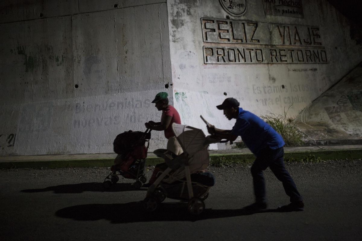 Joel Eduardo Espinar, foreground, and his wife, Yamilet Hernandez, push baby strollers as they start early in the morning towards the next town Arriaga from Pijijiapan, Mexico, on Oct. 26, 2018. Two weeks earlier, the family had fled Honduras and joined the migrant caravan of Central Americans heading north. (Rodrigo Abd / AP)