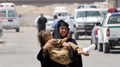 
An Iraqi woman carries her daughter, injured in a bomb blast Tuesday, from a hospital after her treatment. 
 (Associated Press / The Spokesman-Review)