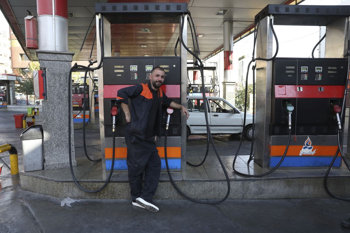 A worker leans against a gasoline pump that has been turned off, at a gas station in Tehran, Iran, Tuesday, Oct. 26, 2021. Gas stations across Iran on Tuesday suffered through a widespread outage of a system that allows consumers to buy fuel with a government-issued card, stopping sales. One semiofficial news agency referred to the incident as a cyberattack.  (Vahid Salemi)