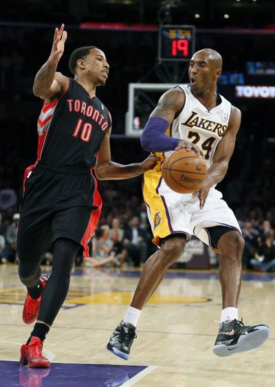 Kobe Bryant, passing around Toronto’s DeMar DeRozan, had eight points and nine rebounds in his season debut for the Lakers. (Associated Press)