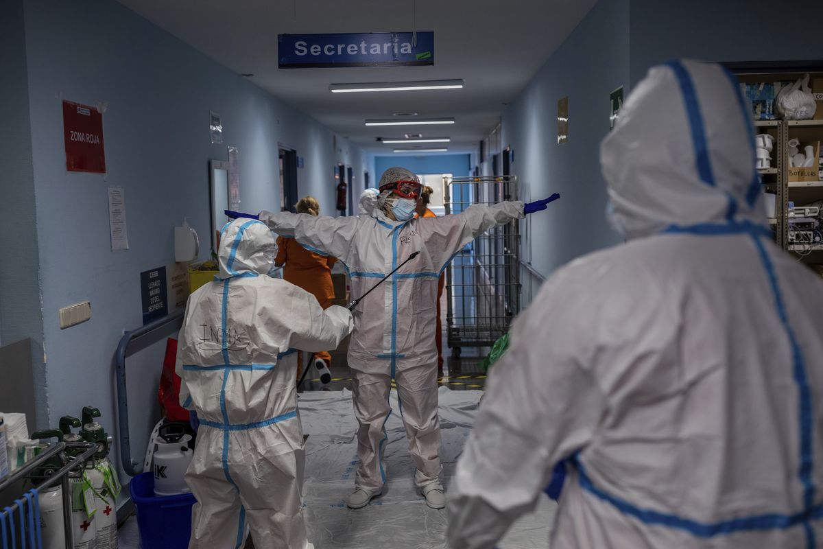 A medical team member is disinfected before leaving the COVID-19 ward at the Severo Ochoa hospital in Leganes, outskirts of Madrid, Spain, Friday, Oct. 9, 2020. At the peak of the first wave, ICU wards were given over to haste, desperation and even cluelessness about what to do. Now, a well-oiled machinery saves some lives and loses others to coronavirus, but without the doomsday atmosphere of March and April. (Bernat Armangue)