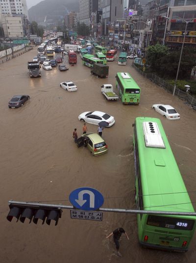People drive vehicles through a flooded road in Seoul, South Korea, on Wednesday. Flooding and landsides have killed at least 44 in the country. (Associated Press)
