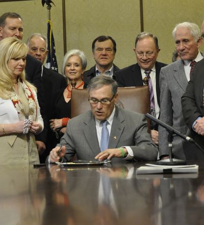 OLYMPIA -- Virginia Graham of Spokane watches as Gov. Jay Inslee signs a bill extending the statute of limitations on prosecuting child sex abuse cases. Behind Graham is Rep. Jeff Holy, R-Cheney, the bill's sponsor; Sen. Mike Padden, R-Spokane Valley is behind Inslee and former Rep. John Ahern is to Inslee's left. (Jim Camden)