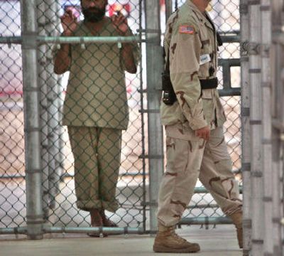 
 A U.S. military guard walks past  a detainee at the maximum security prison at Camp 5 at the Guantanamo Bay U.S. Naval Base, Cuba, in June. 
 (Associated Press / The Spokesman-Review)