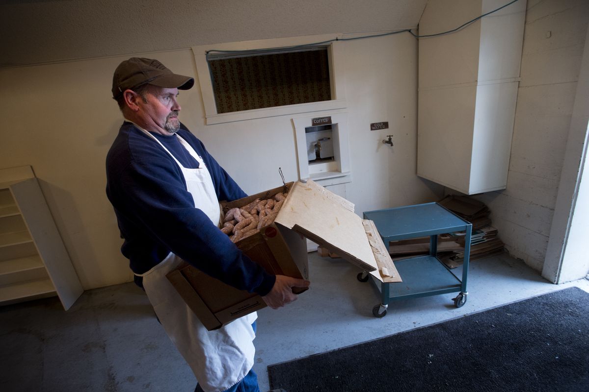 Rodger Moneymaker, 47, of Uniontown, Wash., carries a box of sausages to be smoked Thursday for the community’s annual Sausage Feed. (Tyler Tjomsland)