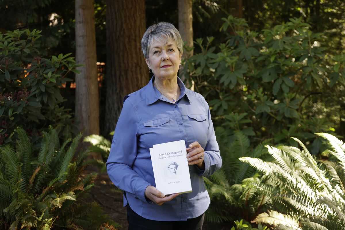 Karen McKnight stands in her backyard on Saturday, in Sammamish, Wash., holding two books written by her brother Ross Bagne of Cheyenne, Wyo. Nearly all COVID-19 deaths in the United States now are in people who weren’t vaccinated like Bagne, a staggering demonstration of how effective the vaccines have been.  (John Froschauer)