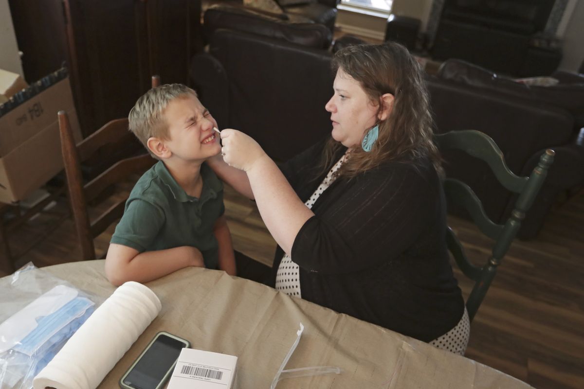 Mendy McNulty swabs the nose of her son, Andrew, 7, Tuesday, July 28, 2020, in their home in Mount Juliet, Tenn. Six thousand U.S. parents and kids are swabbing their noses twice a week to answer some of the most vexing mysteries about the coronavirus. The answers could help determine the safety of in-class education during the pandemic.  (Mark Humphrey)
