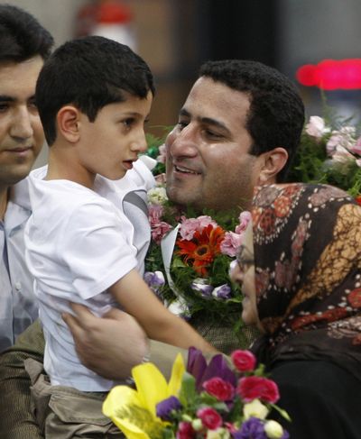 Shahram Amiri, an Iranian scientist who disappeared a year ago, holds his son as he arrives in Iran today. (Associated Press)