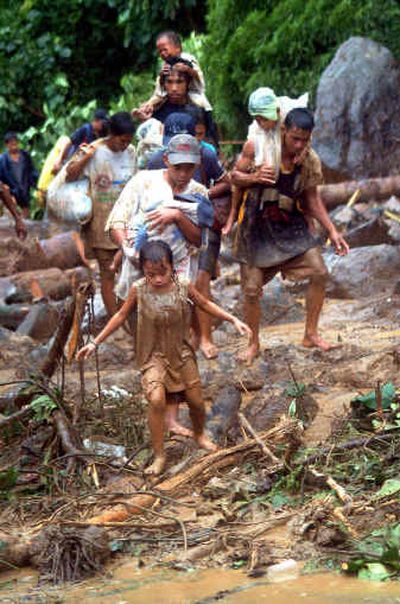 
 Evacuees with their children struggle to walk in the mud at the land slide site Thursday in the typhoon ravaged town of Real, east of Manila, Philippines. 
 (Associated Press / The Spokesman-Review)