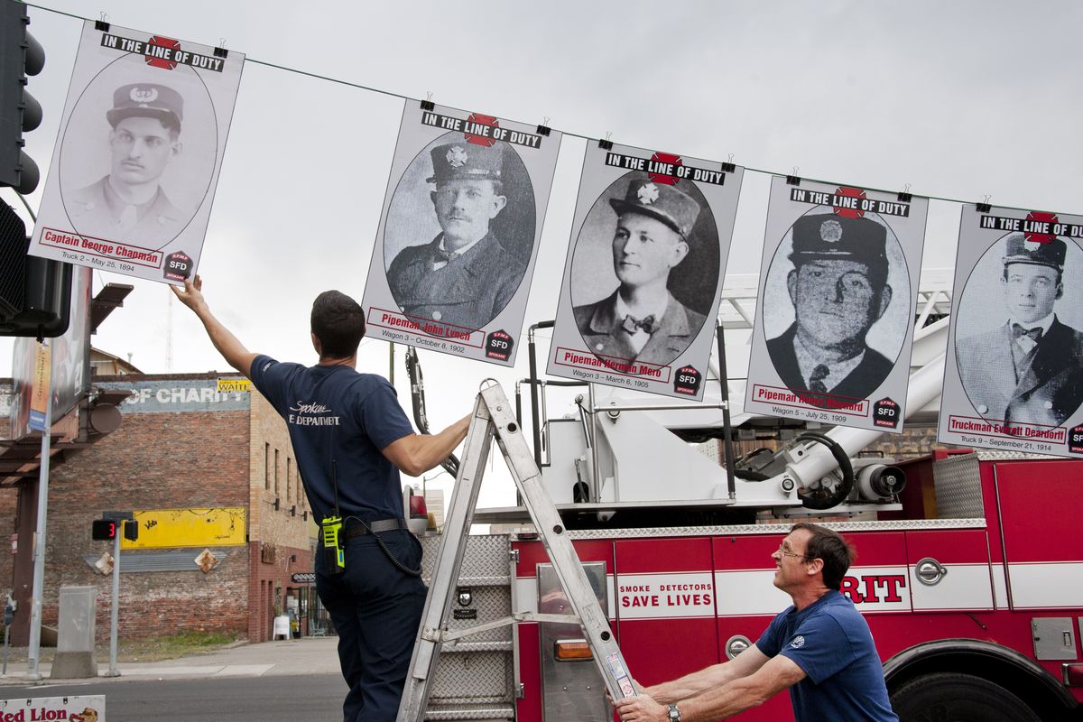 Spokane firefighters Gabe Mills, left, and Jerry Shawn place a picture of Capt. George Chapman into position Monday before the start of the Spokane Firefighters Memorial Project’s dedication ceremony to honor the fallen at the corner of Main Avenue and Division Street in Spokane. Chapman died in the line of duty on May 25, 1894. (Dan Pelle)
