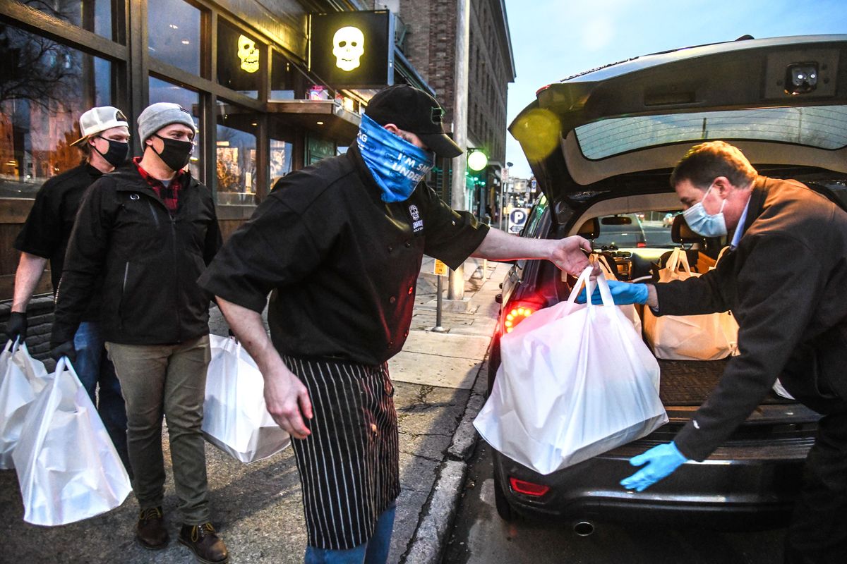 Mike Magurie, of U.S. Foods, right, receives 10 bags containing 65 burritos from Borracho Taco & Tequileria employees, from left, Garrett Wellsandt, Jeremy Tangen and Curtis Olsen, Thursday, Dec. 17, 2020, in downtown Spokane. Spokane native Sydney Sweeney has donated $12,000 to distribute meals from 12 area restaurants to 12 area shelters as part of a special 12 Days of Christmas campaign. $1,000 worth of food is going to a shelter per day. These meals were headed to UGM Crisis Shelter for Women & Children.  (DAN PELLE/THE SPOKESMAN-REVIEW)