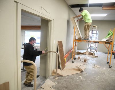 Tod Davin, of Krueger Sheet Metal, left, works on a stairway hand rail, and Garth Seay, of Energized Electric, opens a stack of ceiling tile while finishing the first two rooms at the Cannon Street shelter, Friday, Oct. 30, 2020, near downtown Spokane. A third room will be completed in December. DAN PELLE/THE SPOKESMAN-REVIEW  (DAN PELLE/THE SPOKESMAN-REVIEW)