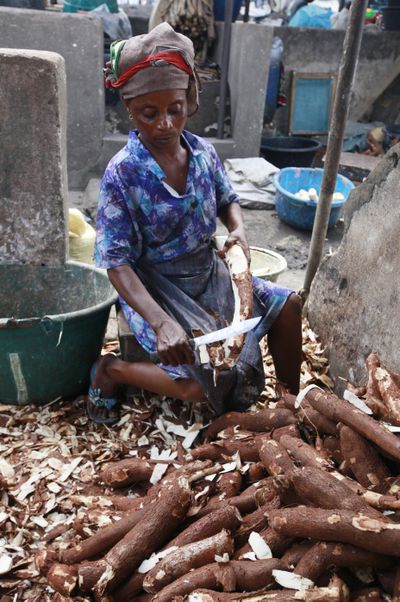 A woman peels cassava to make flour in a market in Lagos, Nigeria. A disease destroying cassava crops has spread out of East Africa. (Associated Press)