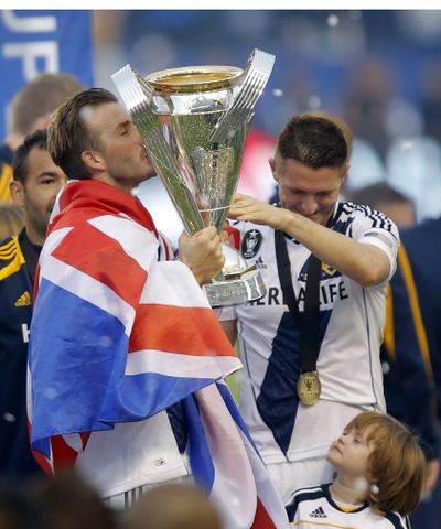 Galaxy's David Beckham, left, and Robbie Keane grab ahold of MLS Cup. (Associated Press)
