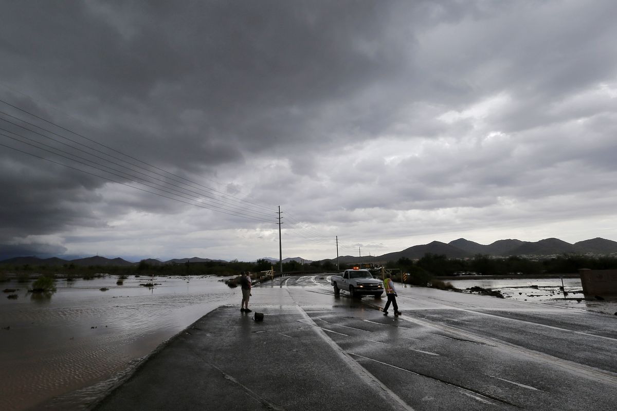 A city of Phoenix official blocks a closed section of road Tuesday as flash flood waters overrun Skunk Creek through the Sonoran Desert in northwestern Phoenix. Flooding from heavy rain in the Phoenix area forced authorities to close several major roads, including a portion of Interstate 17 about 25 miles north of the city. (Associated Press)