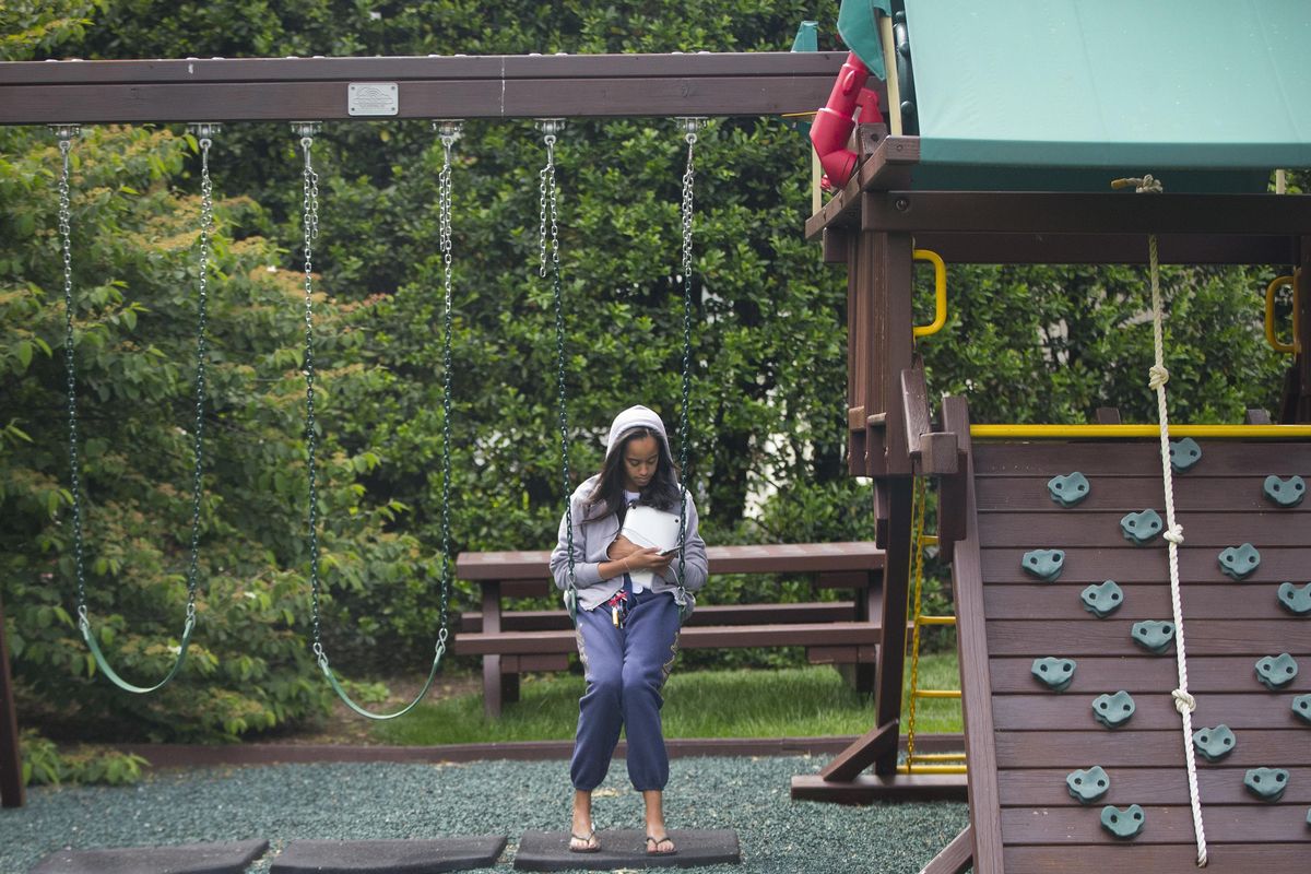 In this photo taken May 18, 2016, Malia Obama uses her phone at the swing and play set on the south grounds of the White House outside of the Oval Office in Washington. President Barack (Pablo Martinez Monsivais / Associated Press)