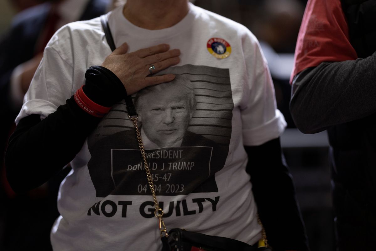 A supporter wearing a shirt featuring the mug shot of former president Donald Trump recites the Pledge of Allegiance during a rally at the Greensboro Coliseum in Greensboro, N.C., on March 2.  (Scott Muthersbaugh/For The Washington Post)