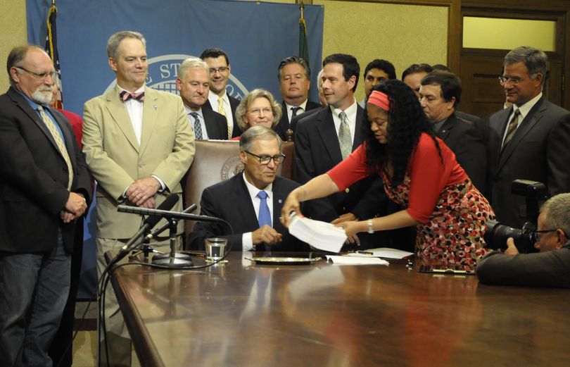 OLYMPIA -- With legislative leaders look on and 20 minutes left in the fiscal year, Gov. Jay Inslee prepares to sign the 2015-17 budget that staff is putting before him.  