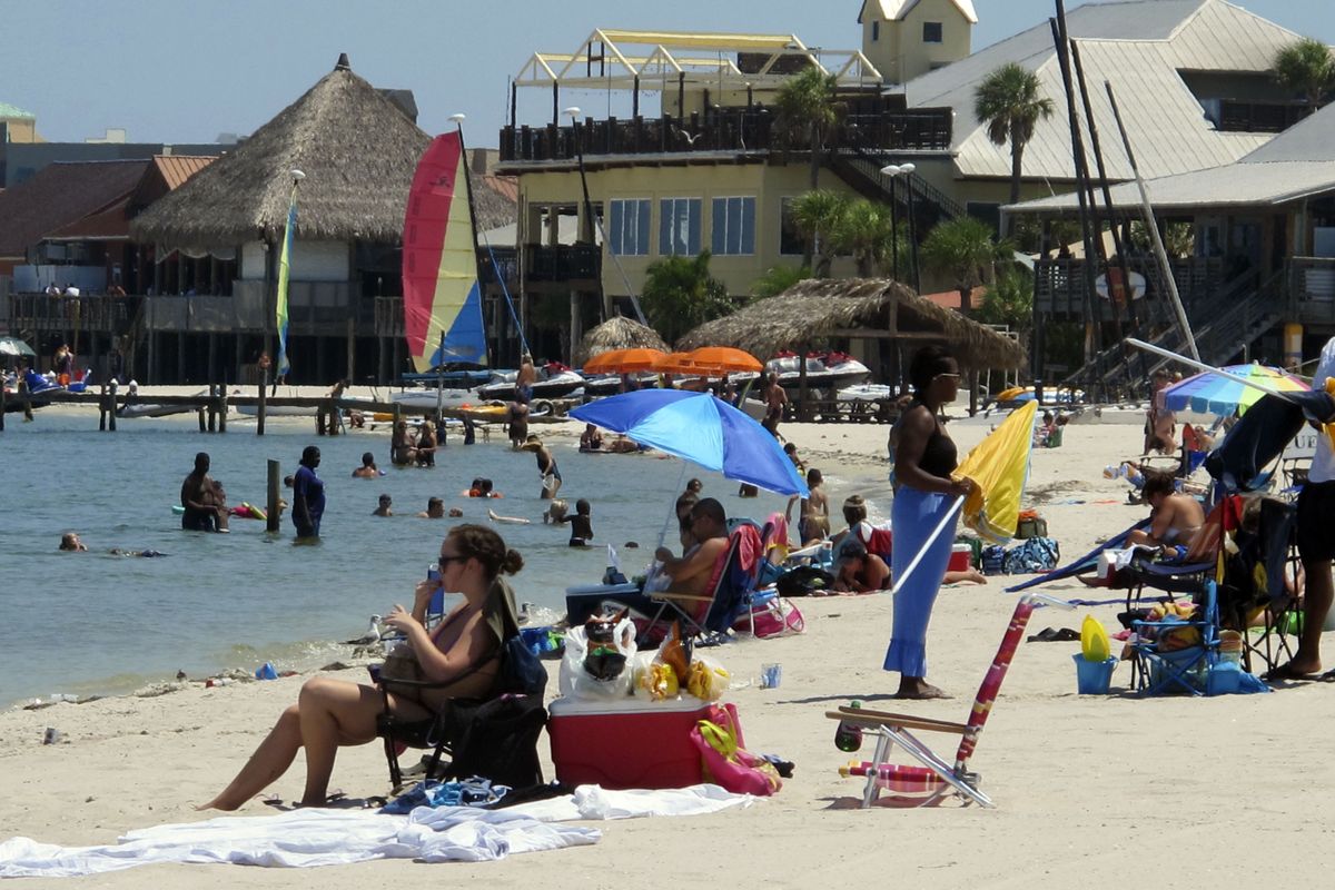 Tourists sit on the beach at Pensacola Beach, Fla., where white sand beaches and turquoise waters of Florida’s Panhandle draw millions of visitors each year. (Associated Press)